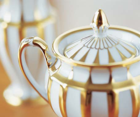 Porzellan-Teekanne mit Deckel, gold-weiß gestreift, auf Holztisch stehend. Fürstenberg Porzellan.