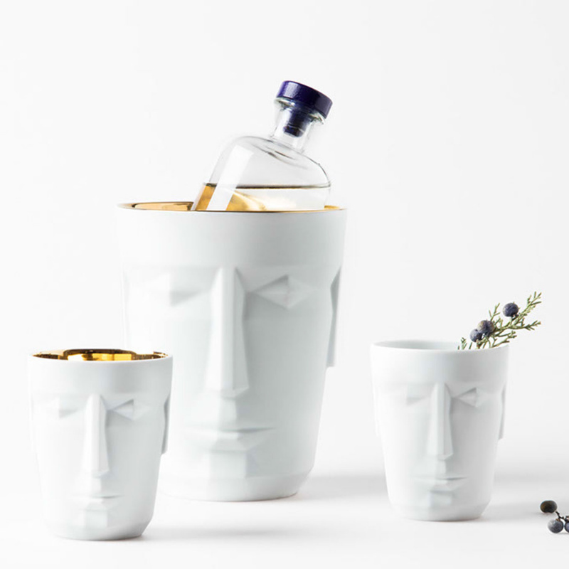 Weiße Porzellantöpfe in Gesichtform, einer enthält Flasche, andere Beerenzweig. Fürstenberg Porzellan.