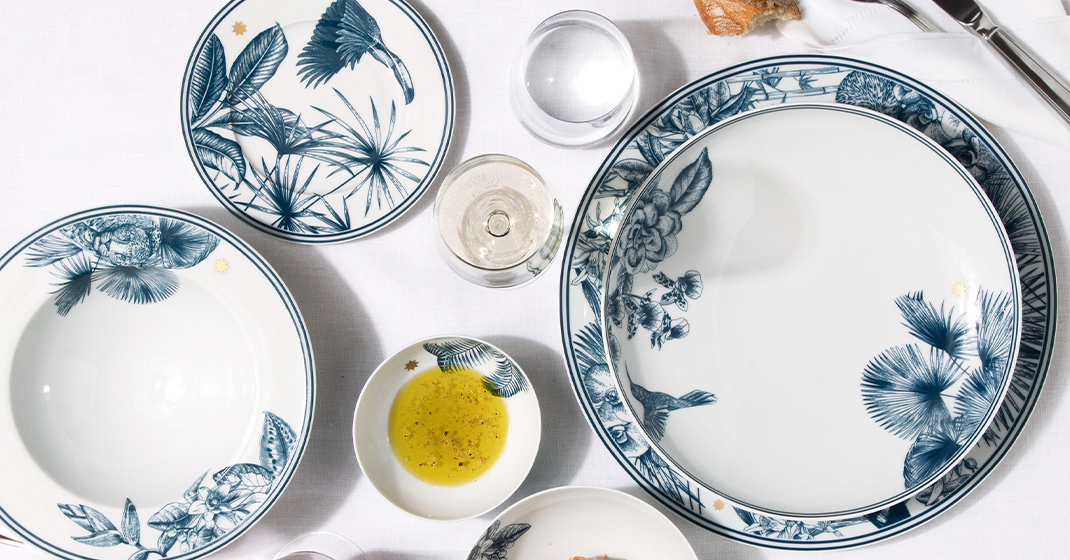 Porzellanteller mit blauen botanischen Illustrationen, auf weißer Tischdecke arrangiert. Fürstenberg Porzellan.