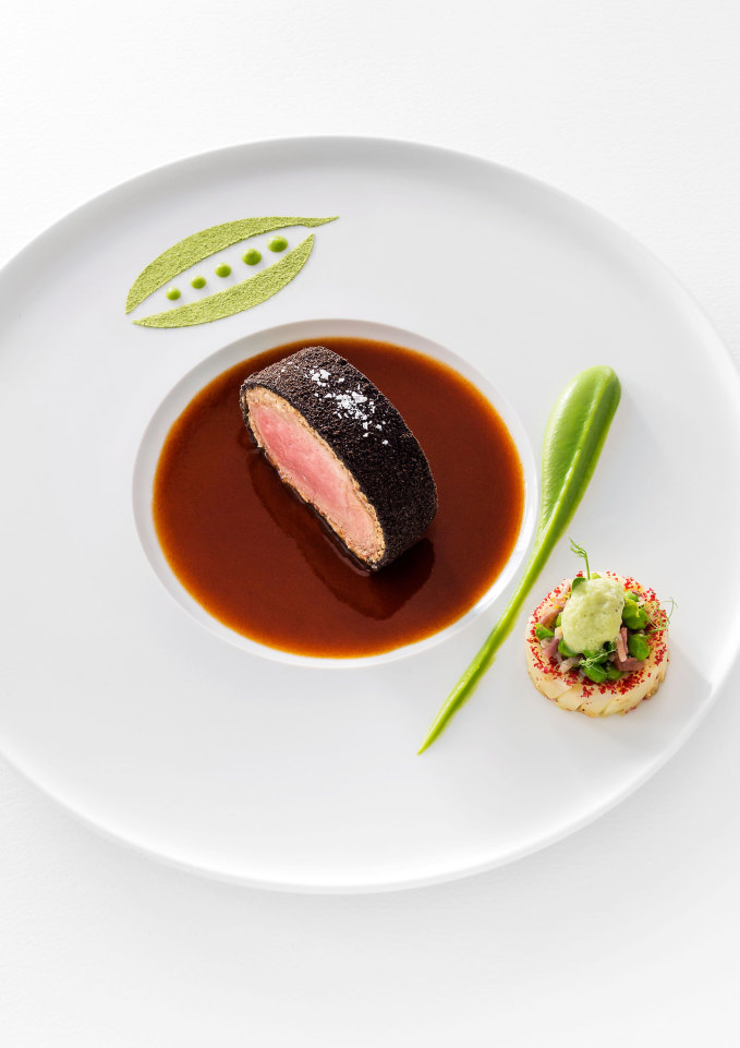 Ein Stück Fleisch auf brauner Sauce, Teller mit kunstvoller grüner Dekoration. Fürstenberg Porzellan.