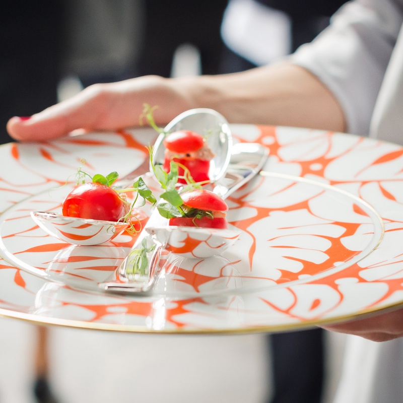Schön dekorierter Teller mit Tomaten-Löffeln, wird von Hand gehalten. Fürstenberg Porzellan.