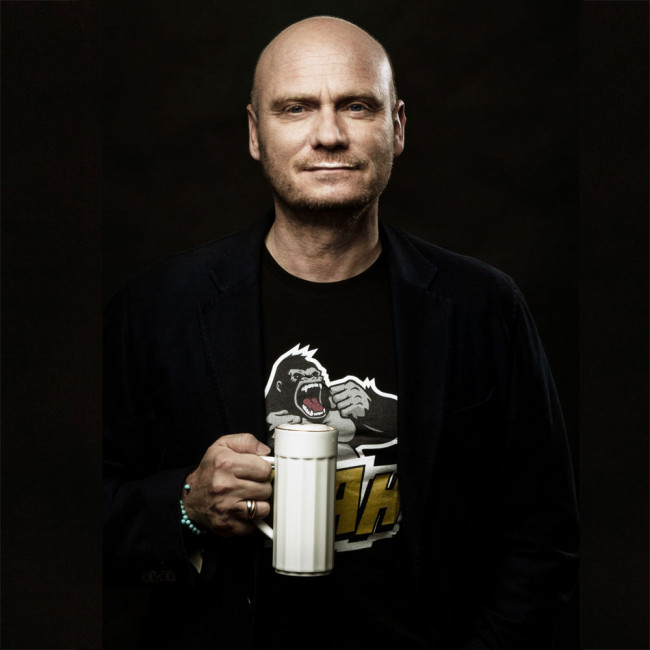 Mann hält weißen Kaffeebecher, trägt schwarzes T-Shirt mit Gorilla-Motiv. Fürstenberg Porzellan.