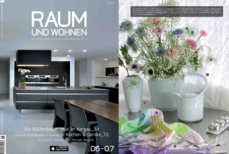 Moderne Küche mit dunkler Einrichtung und Tischgedeck mit weißen Vasen und Blumen. Fürstenberg Porzellan.