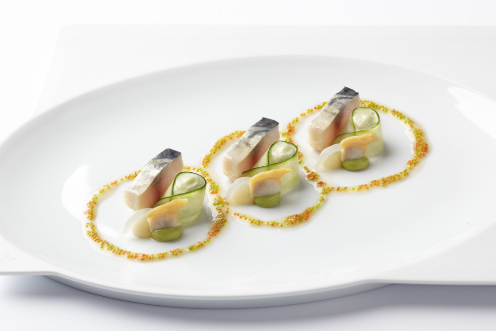 Elegante Speise, dreifach serviert: Fischfilets mit dekorativen Garnierungen auf weißem Teller. Fürstenberg Porzellan.