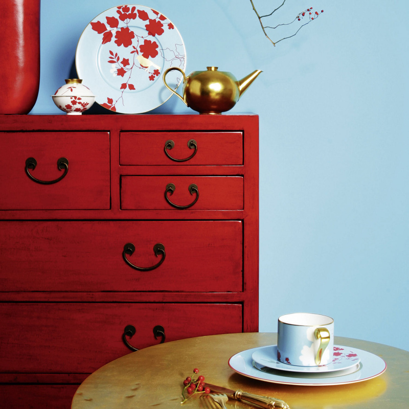 Rote Kommode mit Teekanne, Teller, Tasse und Löffel auf goldenem Tisch. Fürstenberg Porzellan.