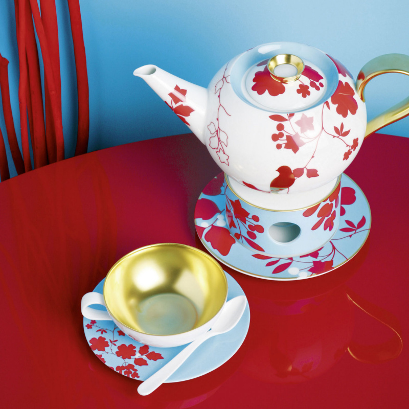 Teekanne und Tasse mit roten Blumenmustern auf rotem Tisch. Fürstenberg Porzellan.