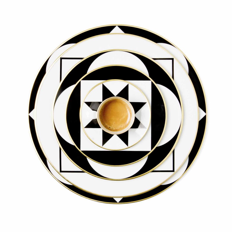 Espressotasse auf geometrisch gemusterten, schwarz-weißen Tellern, elegante Komposition. Fürstenberg Porzellan.