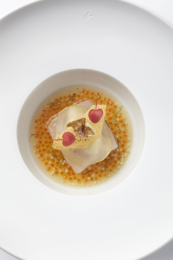 Weißer Porzellanteller mit kunstvoll arrangiertem Gericht, umgeben von orangefarbenem Kaviar. Fürstenberg Porzellan.