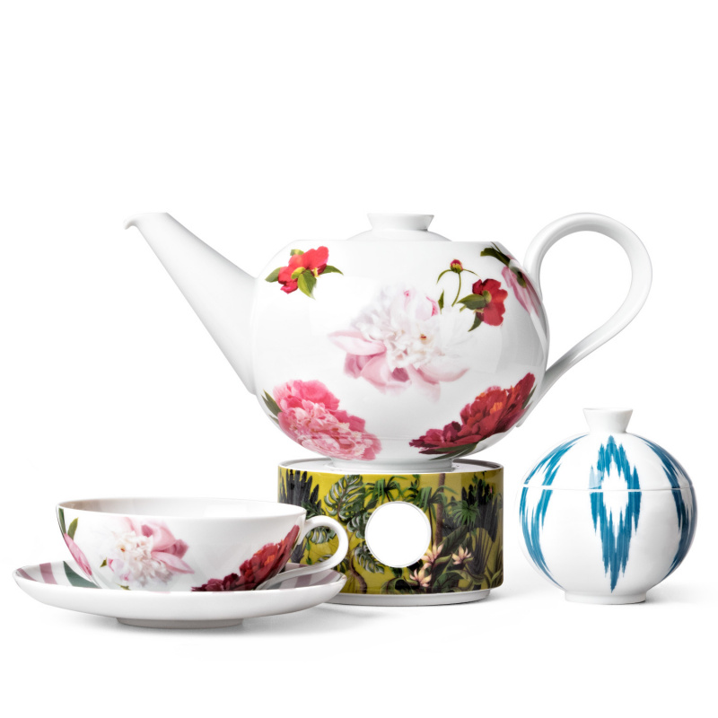 Teekanne mit Blumenmuster auf Stövchen, Tasse daneben, blau-weißes Gefäß rechts. Fürstenberg Porzellan.