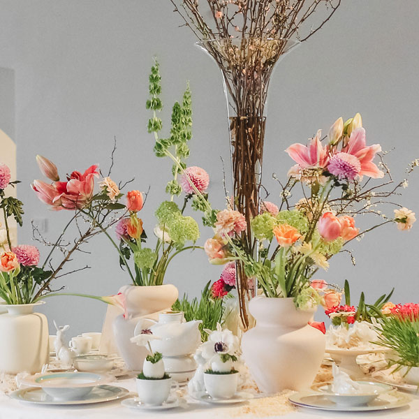 Blumenarrangement auf Tisch mit weißen Vasen und Geschirr, dekorativer Frühlingskontext. Fürstenberg Porzellan.