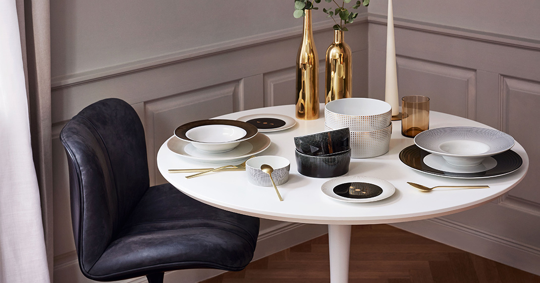 Weißer Tisch, gedeckt mit elegantem Porzellan, goldenen Bestecken und Dekoflaschen. Fürstenberg Porzellan.