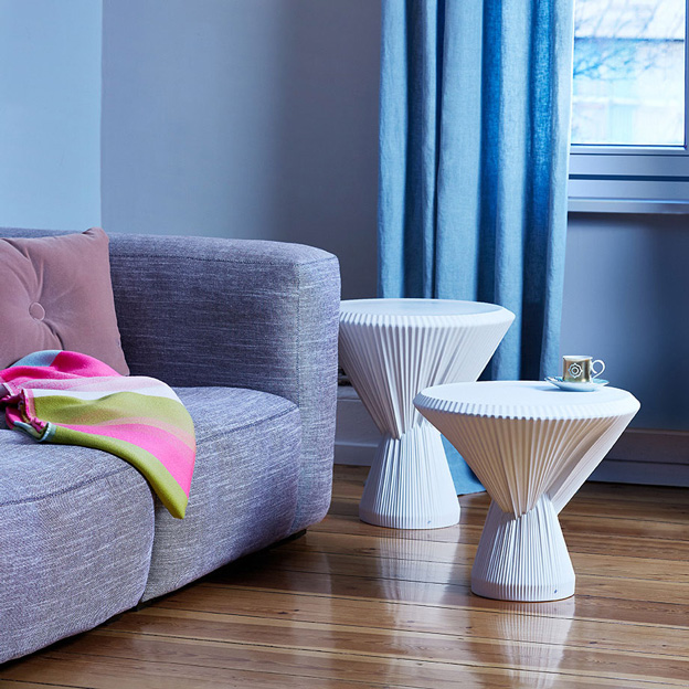 Weiße Beistelltische mit Tasse stehen neben einem grauen Sofa im Wohnzimmer. Fürstenberg Porzellan.
