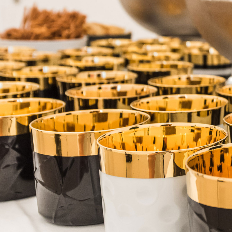 Goldene, glänzende Porzellanbecher mit Reliefmuster, dicht angeordnet auf Tisch. Fürstenberg Porzellan.