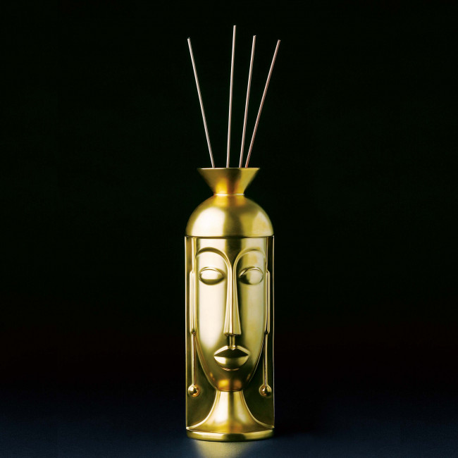 Goldene Skulpturvase mit Gesicht, vier Stäbe oben im dunklen Hintergrund. Fürstenberg Porzellan.