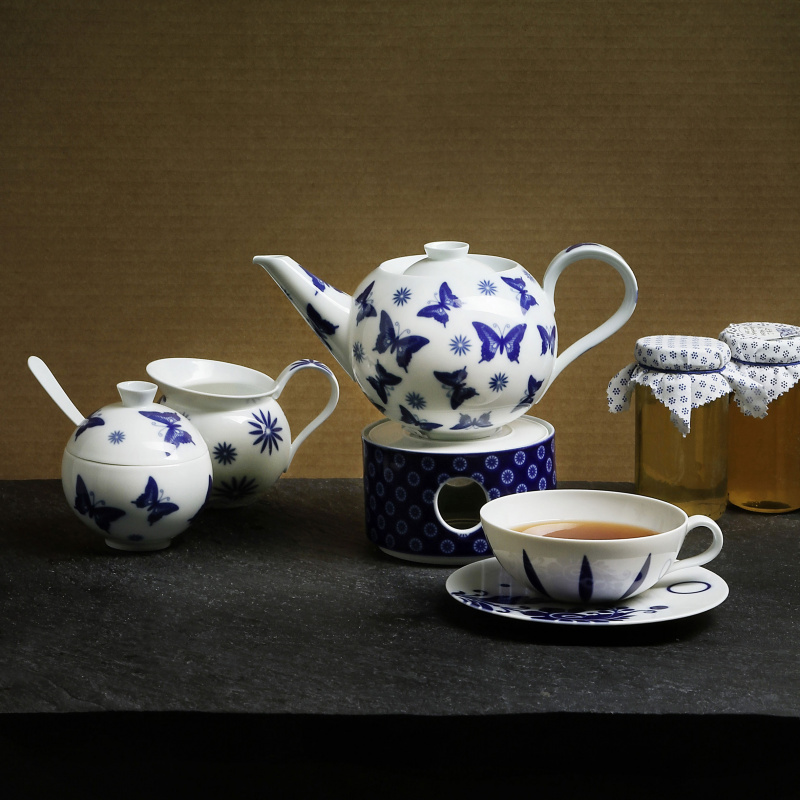 Teekanne mit blauen Schmetterlingen auf Stövchen, Teetasse und Honiggläser. Fürstenberg Porzellan.