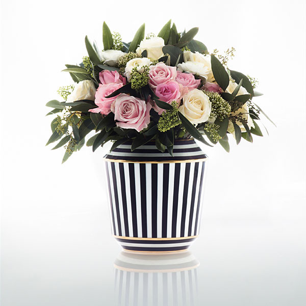 Gestreifte Vase mit Rosen und Eukalyptuszweigen, steht auf einer glänzenden Oberfläche. Fürstenberg Porzellan.