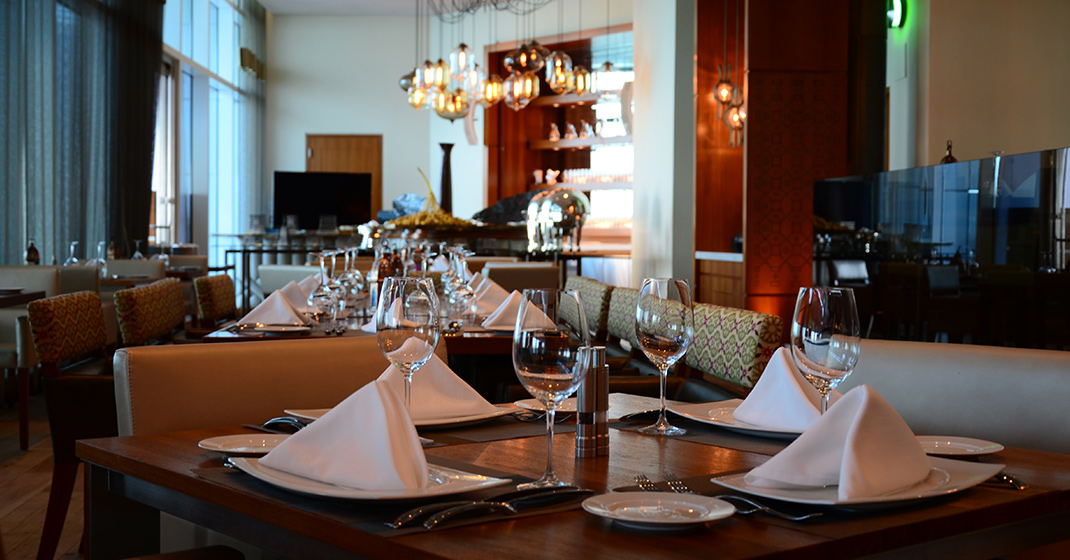 Tisch gedeckt mit Gläsern und Servietten in elegantem Restaurant; warme Beleuchtung. Fürstenberg Porzellan.