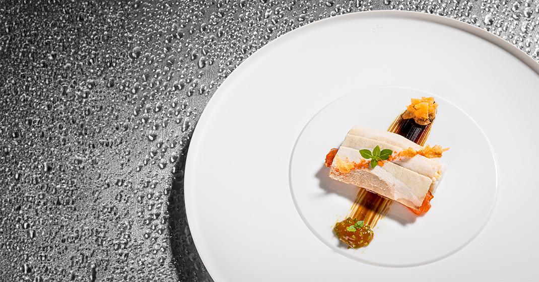 Fein gedeckter, moderner Teller mit kunstvoll angerichtetem Fisch und Gewürzen. Fürstenberg Porzellan.