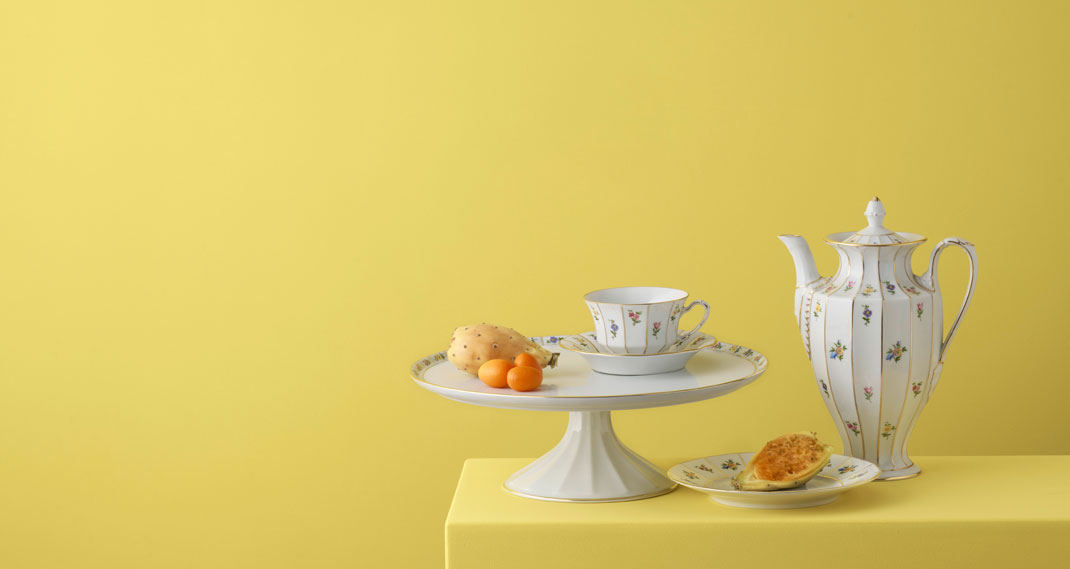 Porzellan-Kaffeeservice mit Blumenmuster und Gebäck auf gelbem Hintergrund. Fürstenberg Porzellan.