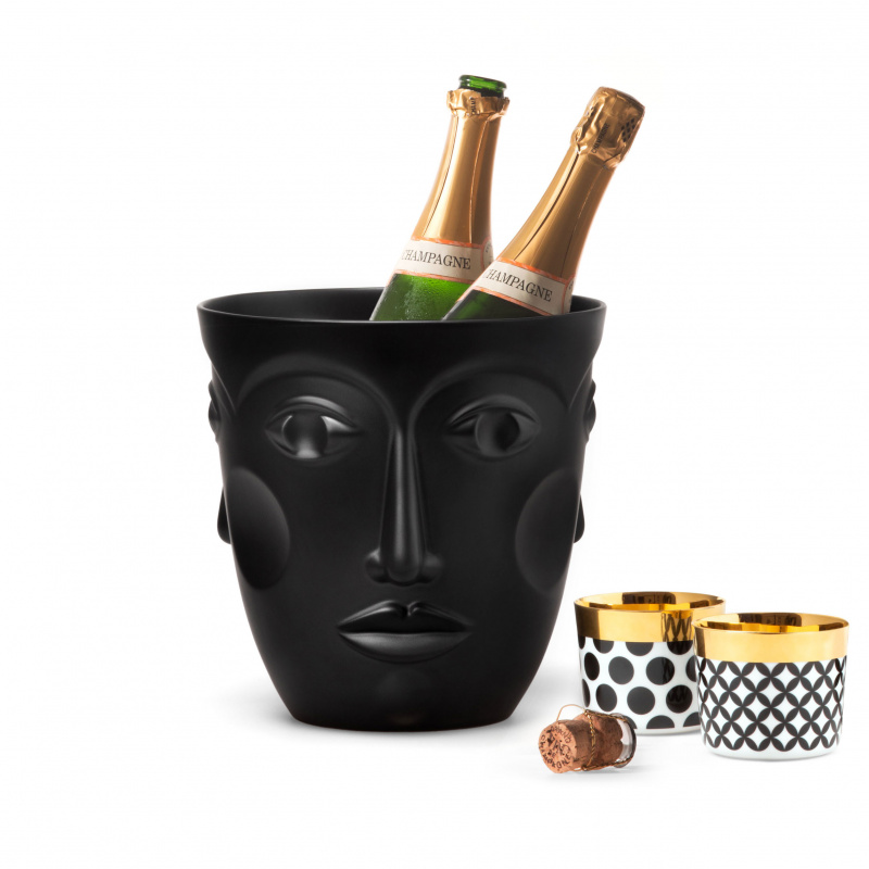 Schwarzer Eiskübel mit Gesichtsmotiv hält zwei Champagnerflaschen, daneben Tassen. Fürstenberg Porzellan.