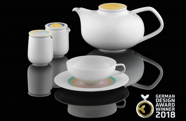 Teekanne, Tasse, Untertasse, Milch- und Zuckergefäß reflektieren beleuchtet auf schwarzem Hintergrund. German Design Award Winner 2018. Fürstenberg Porzellan.