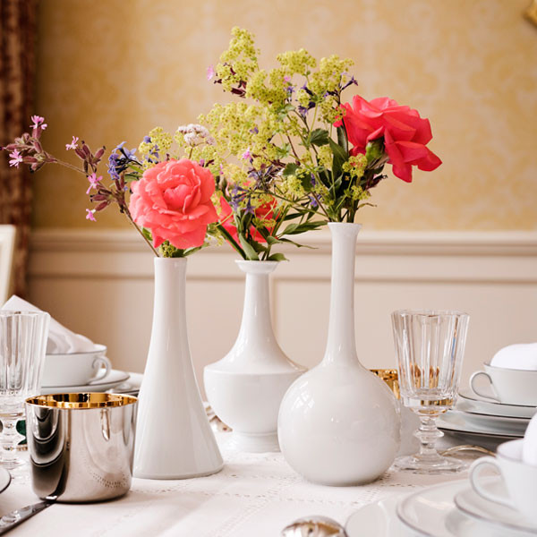 Weiße Vasen mit bunten Blumen auf elegant gedecktem Tisch. Fürstenberg Porzellan.
