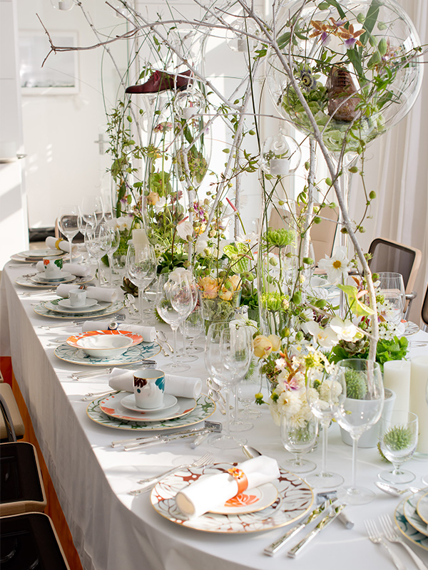 Festlich gedeckter Tisch mit buntem Geschirr, Blumenarrangements und Glasdekoration. Fürstenberg Porzellan.