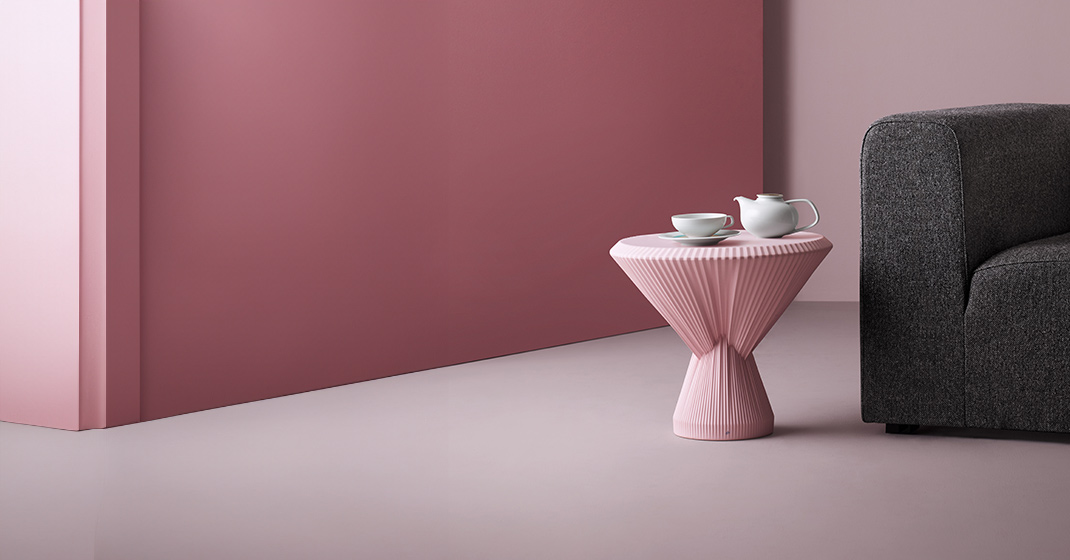Beistelltisch mit Teetasse und Kanne neben grauem Sofa, rosa Wand. Fürstenberg Porzellan.