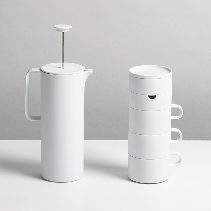 Weißer Porzellan-Kaffeebereiter neben gestapelten Tassen, minimalistisch gestaltet. Fürstenberg Porzellan.