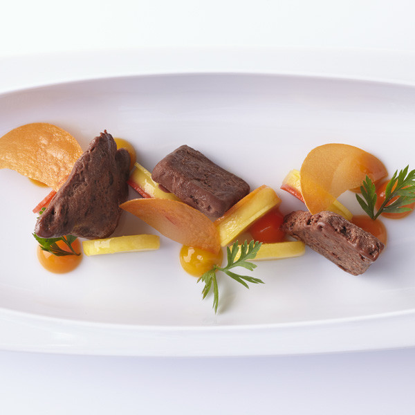 Gourmet-Gericht präsentiert dekorativ auf ovalem weißen Teller mit farbigem Gemüsearrangement. Fürstenberg Porzellan.