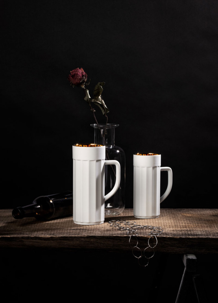 Zwei weiße Tassen stehen auf Holztisch vor Vase mit vertrockneter Rose. Fürstenberg Porzellan.