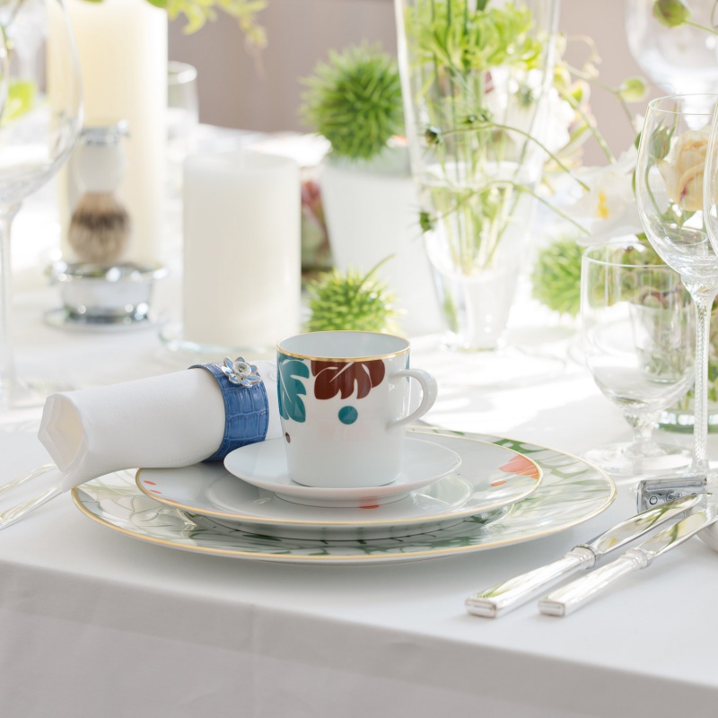 Tasse mit buntem Muster steht auf Teller, umgeben von elegant gedecktem Tisch. Fürstenberg Porzellan.