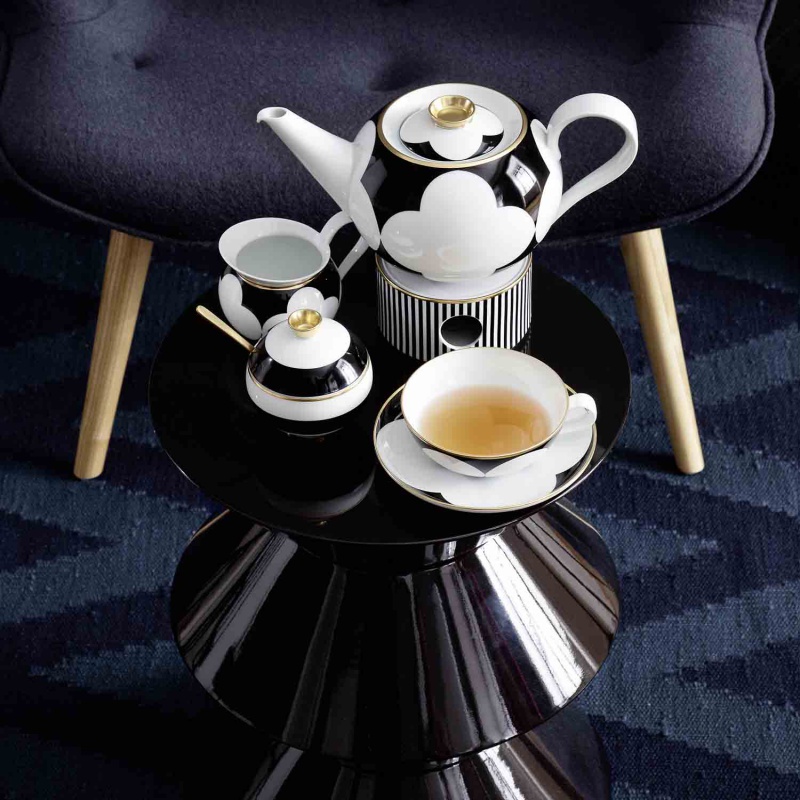 Porzellan-Teeservice steht auf schwarzem Tisch, enthält Teekanne, Tasse und Zuckerdose. Fürstenberg Porzellan.