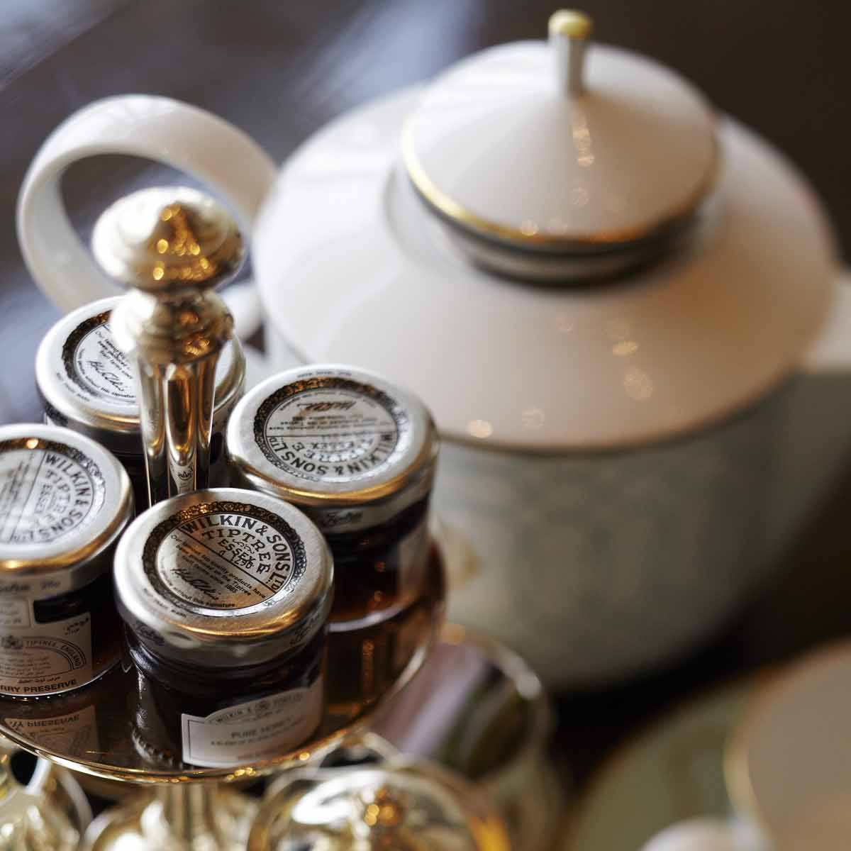 Weiße Teekanne neben Konfitürengläsern auf einem metallenen Ständer. Fürstenberg Porzellan.