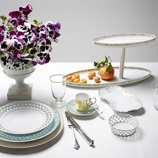 Tafelgedeck mit violetten Blumen, Geschirr und Besteck auf hellem Tisch. Fürstenberg Porzellan.