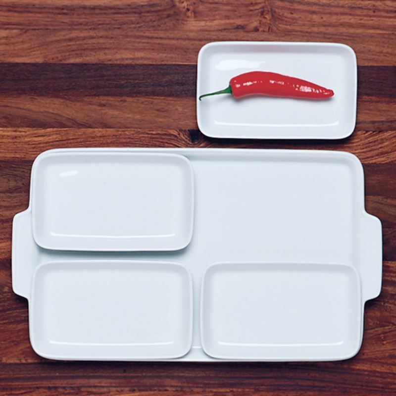 Weiße Porzellanteller auf Holztisch; kleiner Teller mit roter Chilischote. Fürstenberg Porzellan.