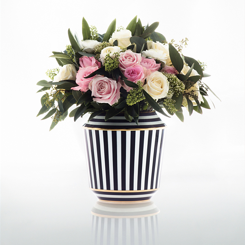 Schwarz-weiß gestreifte Vase, gefüllt mit rosa und weißen Rosen, grünes Laub. Fürstenberg Porzellan.