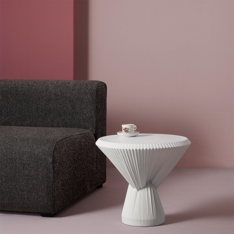 Weiße strukturierte Tischvase hält Tasse mit Blumenmuster vor grauem Sofa. Fürstenberg Porzellan.